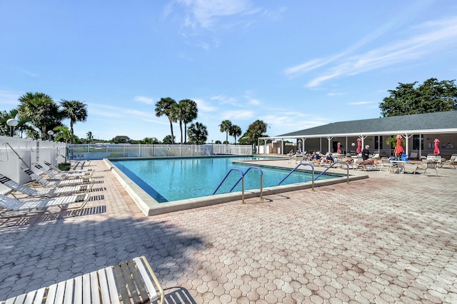 community pool with a patio area and fence