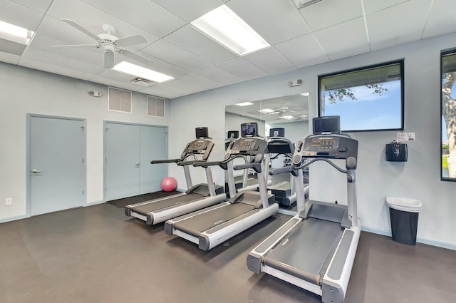 gym with a ceiling fan, visible vents, a paneled ceiling, and baseboards