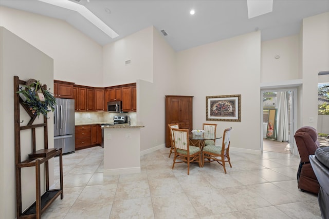 tiled dining area featuring a skylight and high vaulted ceiling