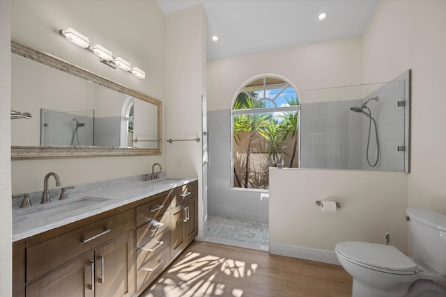 bathroom with vanity, hardwood / wood-style flooring, toilet, and tiled shower