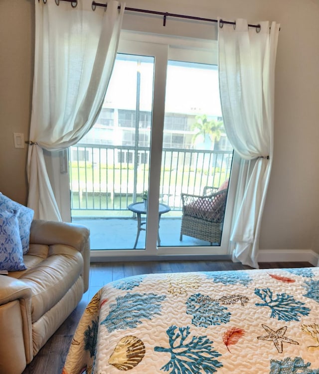 bedroom featuring multiple windows, hardwood / wood-style flooring, and access to outside