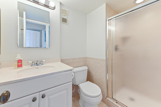 bathroom featuring tile patterned floors, toilet, an enclosed shower, and tile walls