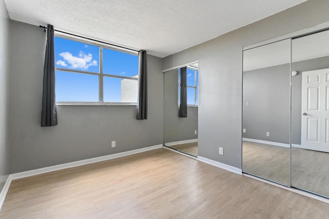 unfurnished bedroom with a textured ceiling and light wood-type flooring