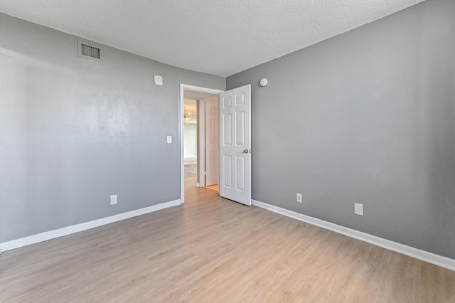 unfurnished room featuring a textured ceiling and light wood-type flooring