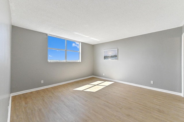 unfurnished room with hardwood / wood-style flooring and a textured ceiling