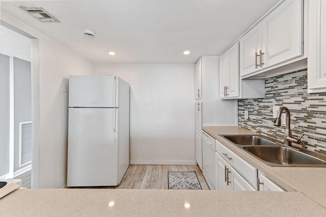 kitchen with sink, white cabinets, decorative backsplash, white appliances, and light hardwood / wood-style flooring