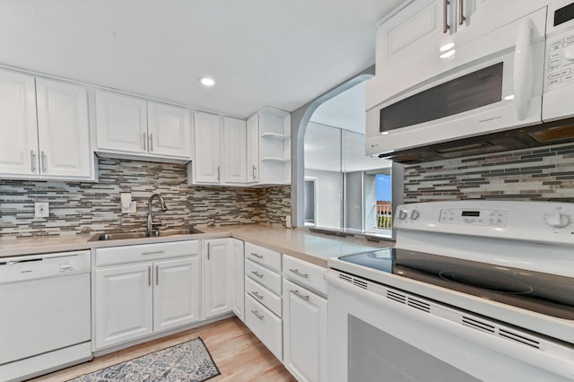 kitchen with sink, white cabinetry, tasteful backsplash, light wood-type flooring, and white appliances