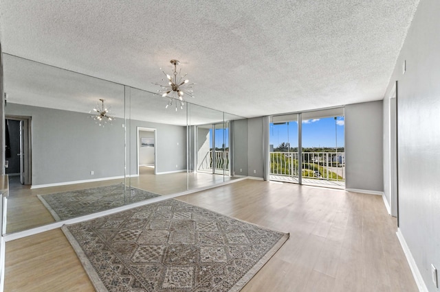 unfurnished room with an inviting chandelier, hardwood / wood-style flooring, floor to ceiling windows, and a textured ceiling