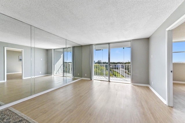 spare room featuring hardwood / wood-style floors, a wall of windows, and a textured ceiling