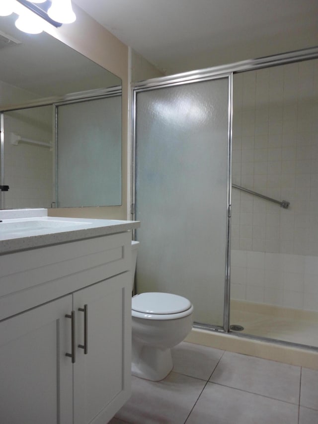 bathroom featuring tile patterned flooring, vanity, an enclosed shower, and toilet