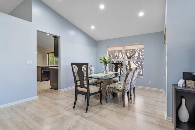 dining room with a healthy amount of sunlight, high vaulted ceiling, and light hardwood / wood-style flooring