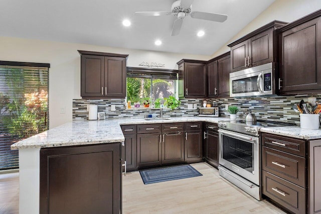 kitchen featuring lofted ceiling, sink, tasteful backsplash, kitchen peninsula, and stainless steel appliances