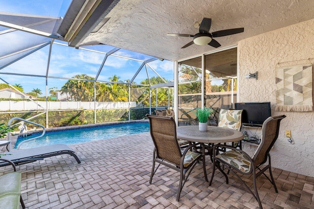 view of pool featuring ceiling fan, glass enclosure, and a patio area