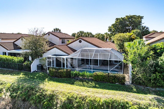 back of house with a yard, central AC unit, a swimming pool, and glass enclosure