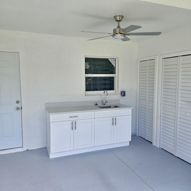 interior space with white cabinetry, sink, and ceiling fan