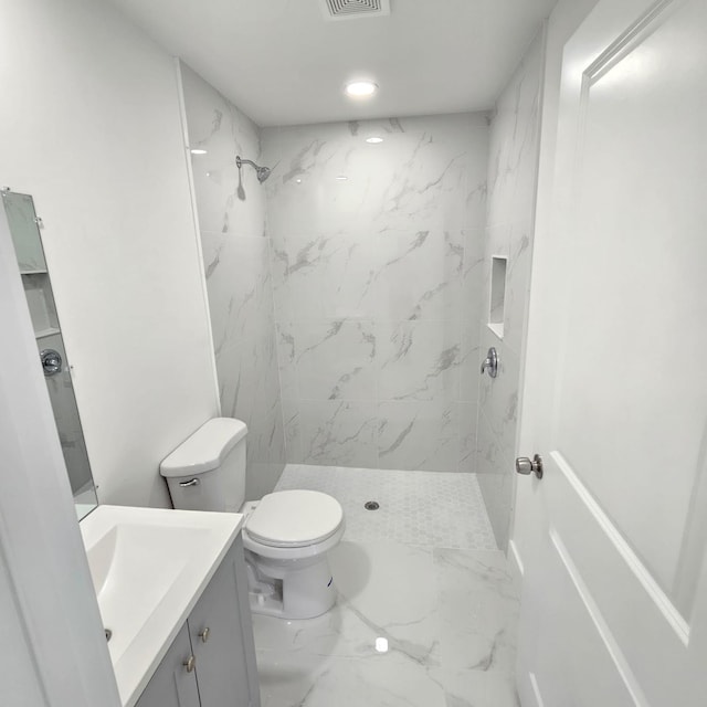 bathroom featuring tiled shower, vanity, and toilet