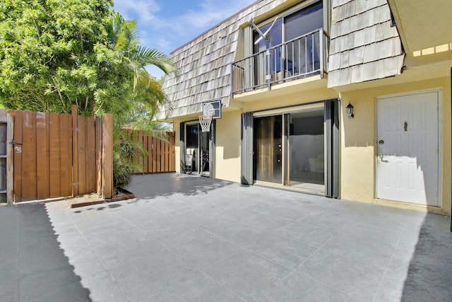 exterior space featuring mansard roof, fence, and stucco siding