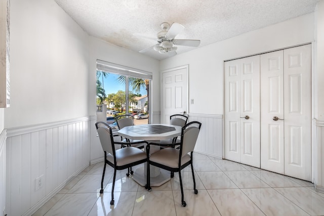 tiled dining space with ceiling fan and a textured ceiling