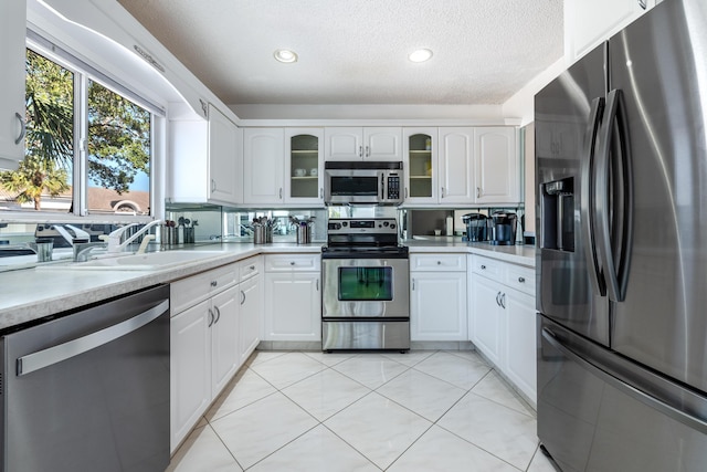 kitchen with light tile patterned floors, appliances with stainless steel finishes, sink, and white cabinets