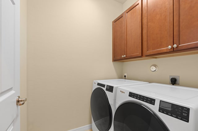 laundry area featuring baseboards, cabinet space, and washing machine and clothes dryer