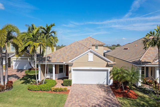 view of front of property featuring a garage, a front yard, decorative driveway, and stucco siding