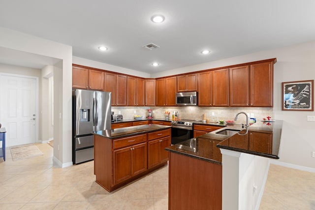 kitchen featuring stainless steel appliances, a sink, visible vents, decorative backsplash, and dark stone countertops