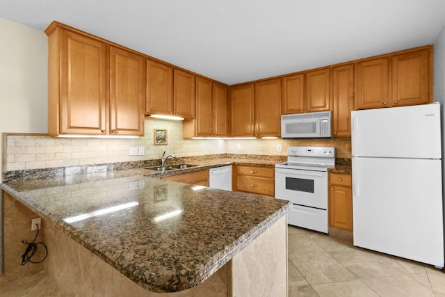 kitchen with sink, dark stone counters, light tile patterned floors, kitchen peninsula, and white appliances