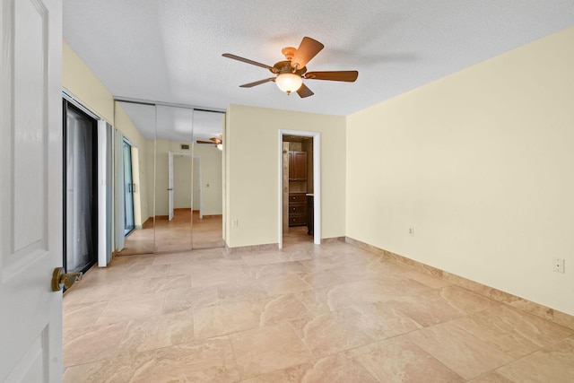 unfurnished room with ceiling fan and a textured ceiling