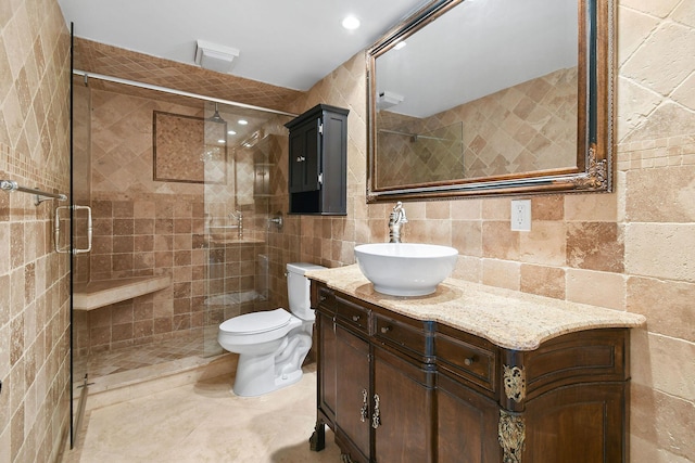 bathroom featuring a shower with door, vanity, tile walls, and toilet