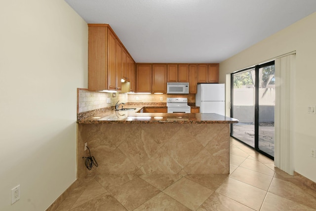 kitchen featuring stone countertops, sink, decorative backsplash, kitchen peninsula, and white appliances