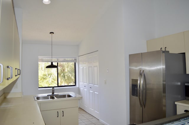 kitchen featuring light tile patterned flooring, decorative light fixtures, sink, kitchen peninsula, and stainless steel refrigerator with ice dispenser