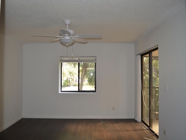 unfurnished room with ceiling fan, a wealth of natural light, a textured ceiling, and dark hardwood / wood-style flooring