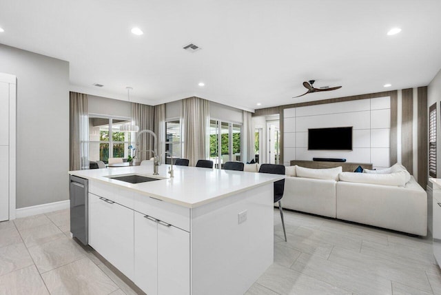 kitchen featuring white cabinetry, sink, a kitchen breakfast bar, stainless steel dishwasher, and a center island with sink