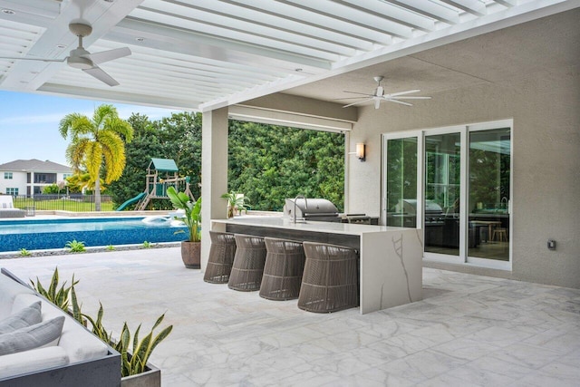 view of patio with an outdoor kitchen, a playground, area for grilling, a bar, and a fenced in pool