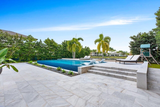 view of pool with a patio area and a playground