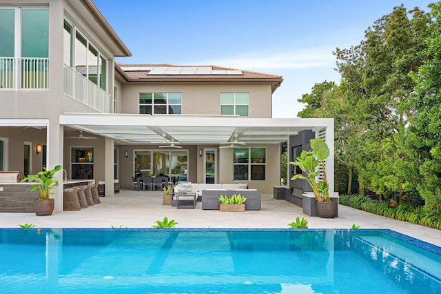 back of house with solar panels, a balcony, ceiling fan, an outdoor living space, and a patio area