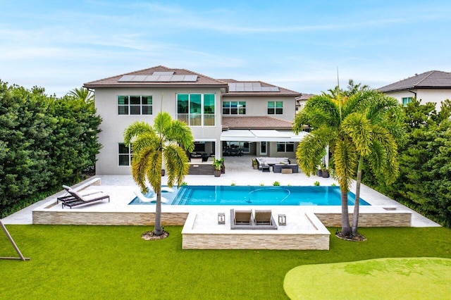 back of house featuring a lawn, outdoor lounge area, a patio area, and solar panels