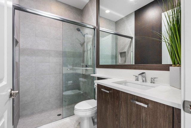 bathroom featuring vanity, a shower with door, and toilet