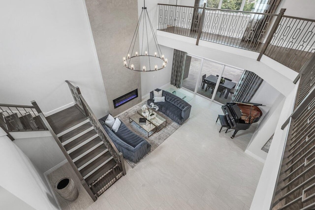 living room with a towering ceiling, a fireplace, and an inviting chandelier