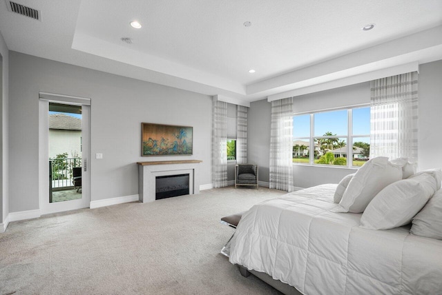 bedroom featuring carpet flooring, a tray ceiling, and access to outside