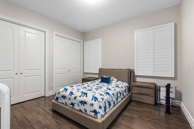 bedroom with dark hardwood / wood-style floors and two closets