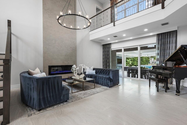 living room with a high ceiling, a large fireplace, tile patterned flooring, and a notable chandelier