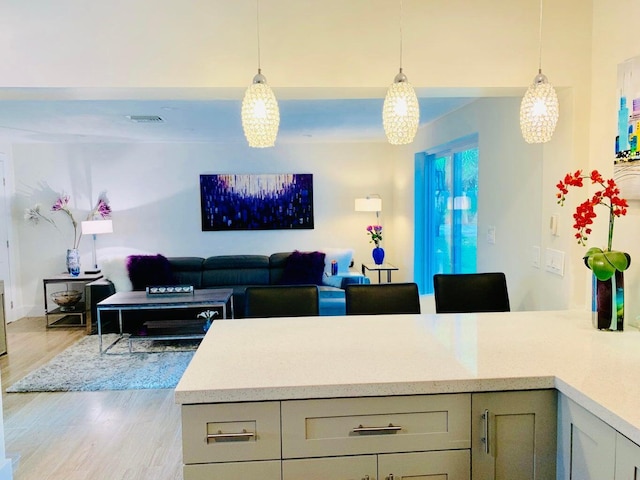 kitchen featuring gray cabinetry, decorative light fixtures, and light wood-type flooring