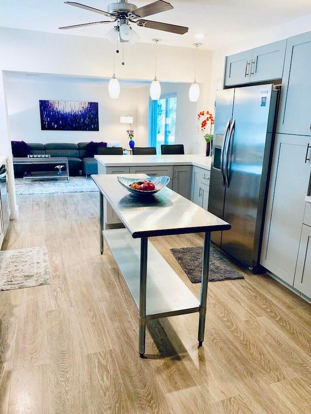 kitchen with stainless steel refrigerator with ice dispenser, pendant lighting, ceiling fan, and light wood-type flooring