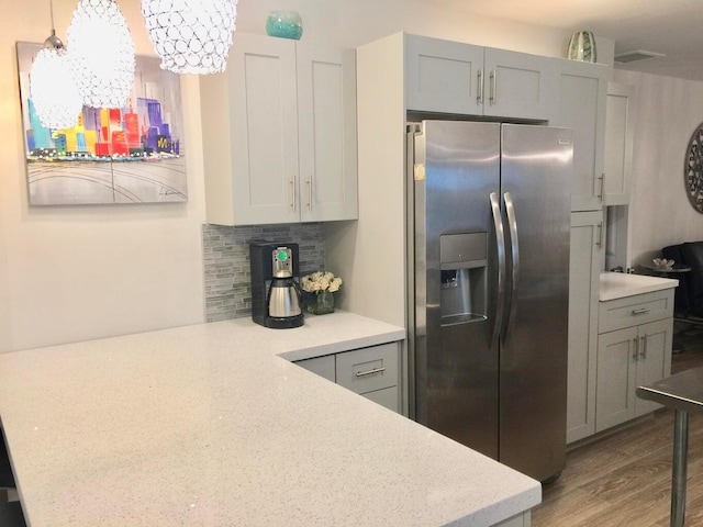 kitchen with stainless steel refrigerator with ice dispenser, decorative light fixtures, tasteful backsplash, and gray cabinetry