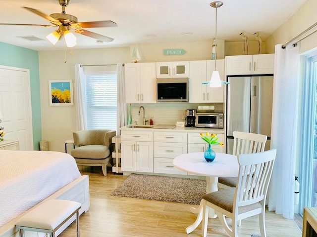 kitchen featuring pendant lighting, tasteful backsplash, white cabinetry, sink, and stainless steel appliances