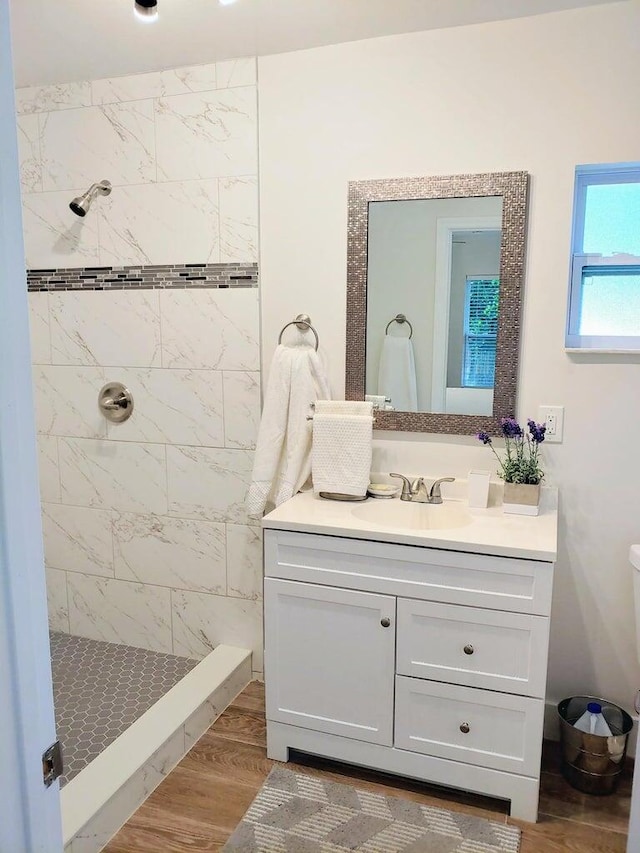 bathroom with vanity, wood-type flooring, and a tile shower