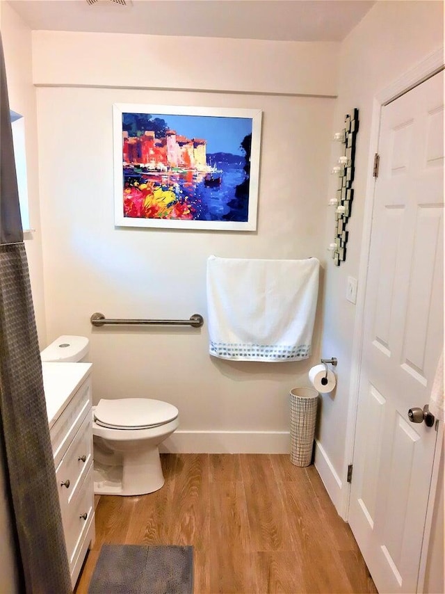 bathroom with hardwood / wood-style flooring, vanity, and toilet