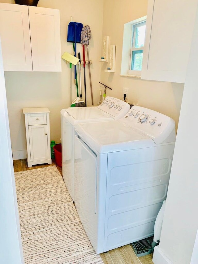 clothes washing area with cabinets and washer and clothes dryer