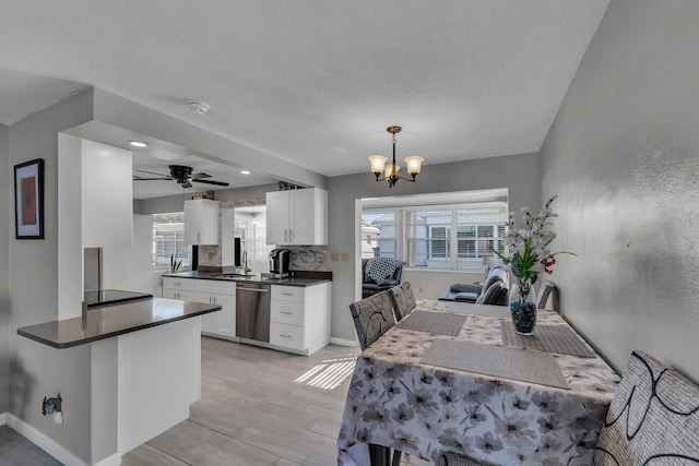 dining area featuring a healthy amount of sunlight, sink, ceiling fan with notable chandelier, and a textured ceiling